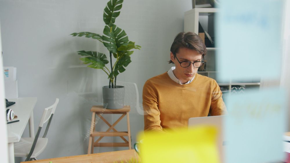 A young man working on a laptop at his desk