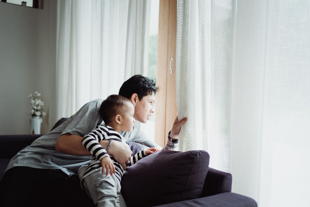 A father and his young son looking out a window together